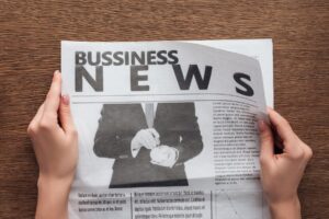 Hands holding business news section of newspaper