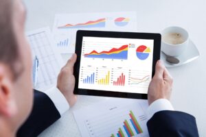 Man looking at data graphs and charts on a tablet and documents