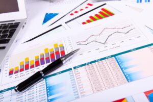 Business graphs and charts on paper with a pen