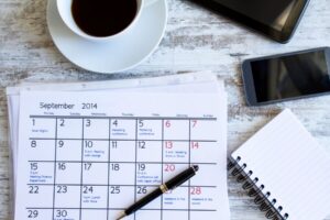 Calendar, pen, notepad and cup of coffee