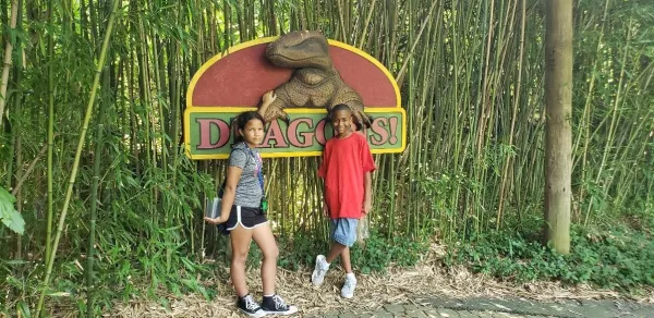 Children standing in front of a Dragons! sign at the zoo.