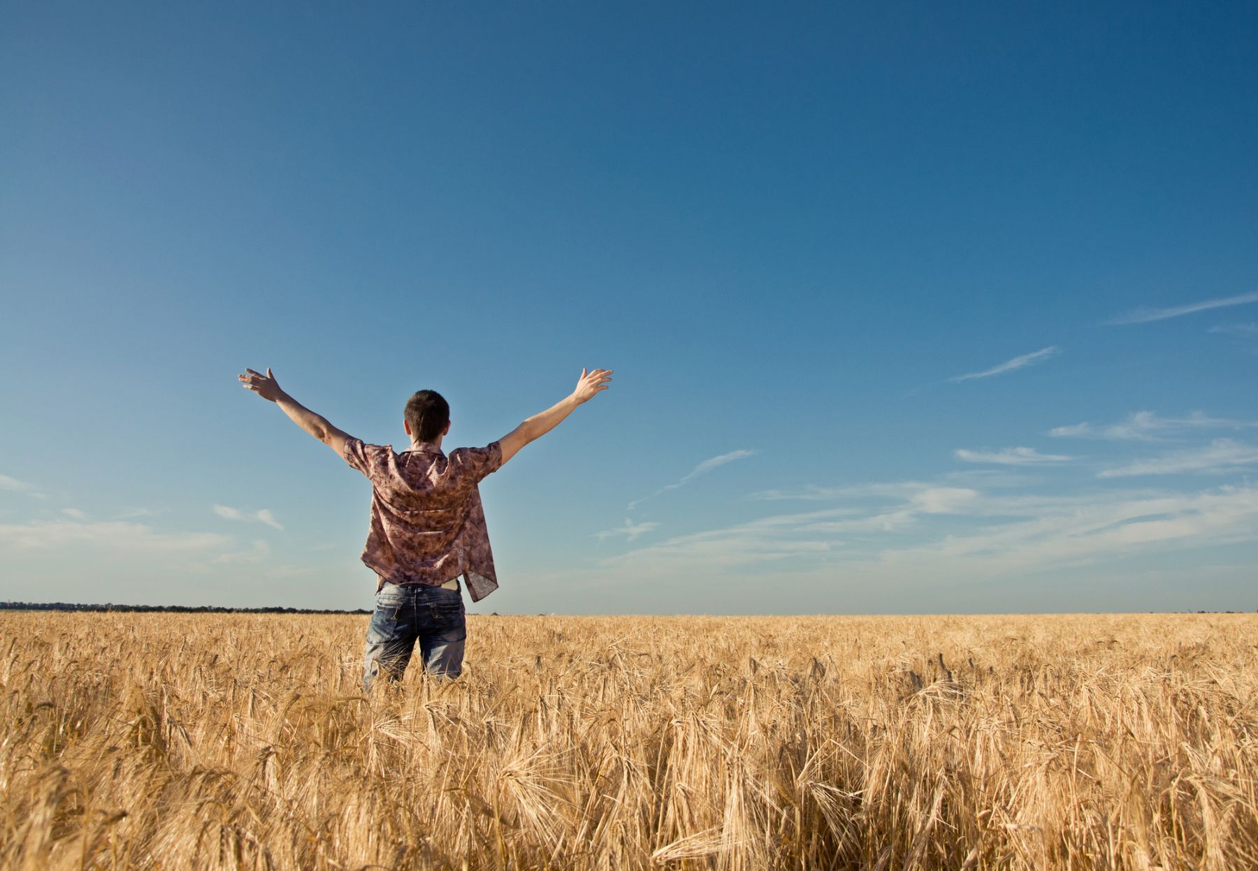 Man standing in a field with arms stretched out