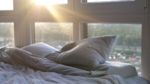 picture of a bed next to a window and sun is coming up