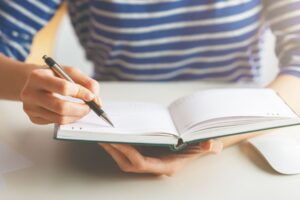 woman sitting down and writing things in her calendar