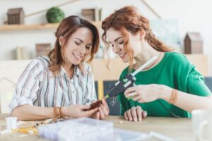 two women gluing something together with hot glue